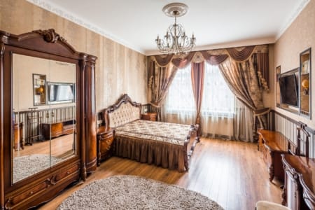 Спальня з дзеркальною шафою та класичним ліжком в апартаментах на площі Данила Галицького