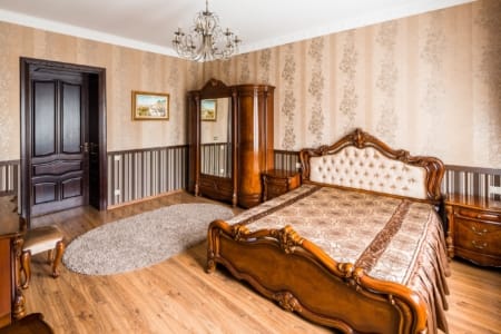Klasyczne łóżko z tapicerowanym wezgłowiem i drewniane drzwi w apartamencie przy placu Danyła Halickiego
