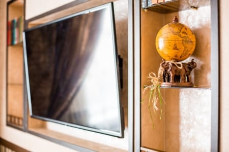Telewizor we wnęce i ozdobny globus na półce w apartamencie przy placu Danyła Halickiego