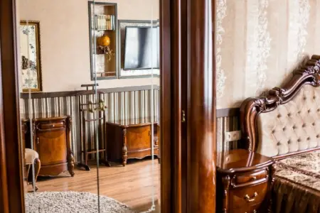 Sypialnia z rzeźbionymi meblami i lustrem w apartamencie przy placu Danyła Halickiego