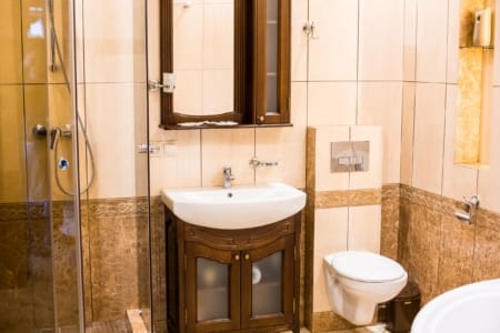Umywalka z drewnianą szafką, podwieszana toaleta i kabina prysznicowa w apartamencie przy placu Danyła Halickiego