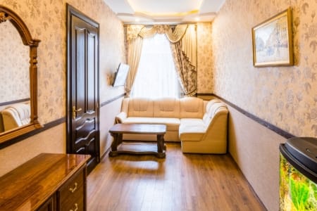 Salon z narożną sofą, lustrem i komodą w mieszkaniu przy placu Danyła Halickiego