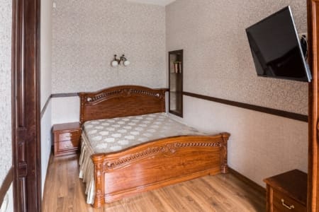 Спальня з дерев'яним різьбленим ліжком і телевізором у квартирі на площі Данила Галицького