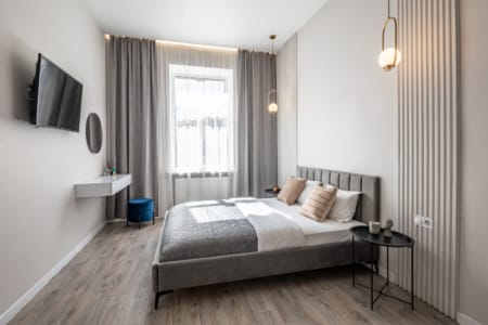 Bedroom with a double bed, TV and window in the apartment on Mentsynskoho Street