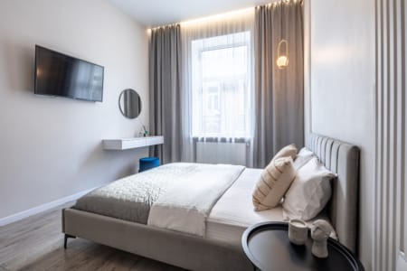 Bedroom with a double bed, curtains and TV in the apartment on Mentsynskoho Street
