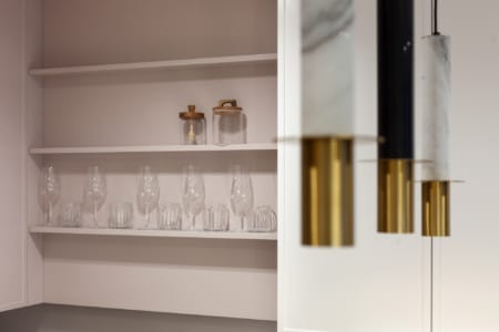 Відкриті полиці з келихами та підвісні світильники на кухні квартири в ЖК «Семицвіт»