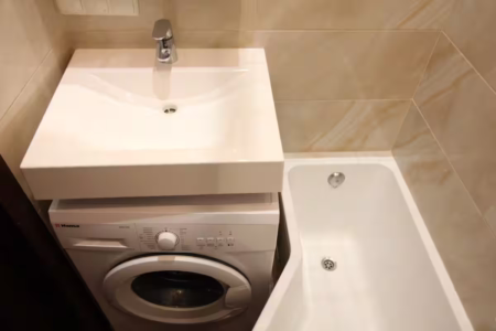 Wanna, umywalka i pralka w łazience kawalerki przy ul. Ohijenki