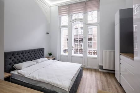 Sypialnia z podwójnym łóżkiem i drzwiami balkonowymi w kawalerce przy ul. Doroszenki