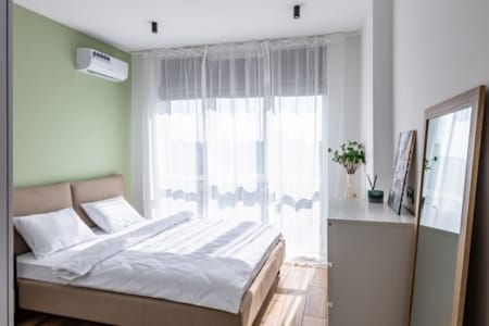 Sypialnia z podwójnym łóżkiem, klimatyzacją i dużym oknem w mieszkaniu w kompleksie Semitsvit