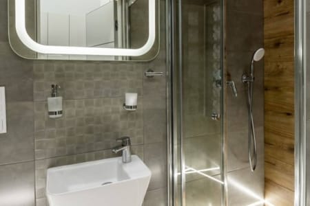 Bathroom with a shower cabin and an illuminated mirror in the studio apartment on Doroshenka Street