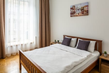 Bedroom with a wooden bed and a painting in the apartment on Krakivska Street, Lviv