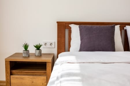 Bed with a purple cushion and a bedside table in the bedroom, Krakivska Street apartment