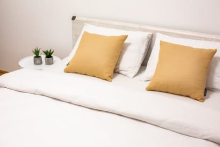 Double bed with yellow cushions in the bedroom of the Krakivska Street apartment