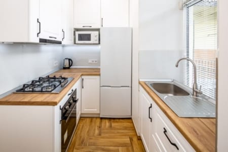 White kitchen with an oven, fridge and sink, Krakivska Street apartment