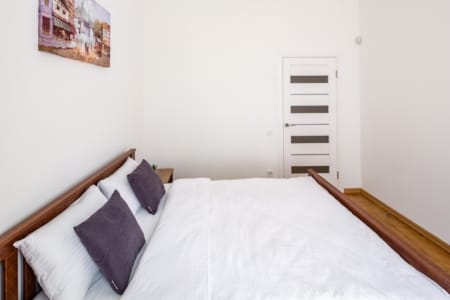 Double bed with purple cushions in the bedroom of the Krakivska Street apartment