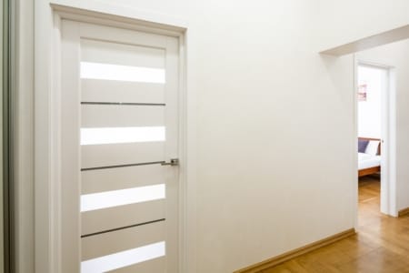 Hallway with white doors and a view into the bedroom, Krakivska Street apartment