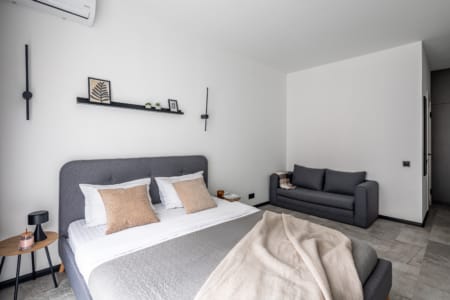 Double bed and sofa in the bright room of the apartment in the Semytsvit complex