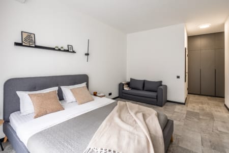 Room with a bed, sofa and built-in wardrobe in the modern apartment in the Semytsvit complex