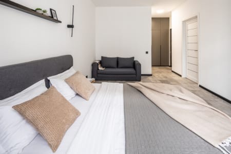 View from the bed to the sofa and entrance door in the modern apartment in the Semytsvit complex