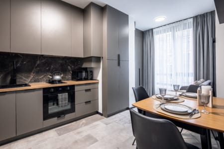 Kitchen with grey units, a marble-effect splashback and a set table in the apartment in the Semytsvit complex