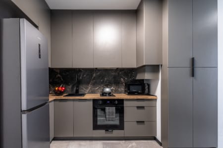 Kitchen with a steel fridge, oven and grey cabinets, apartment in the Semytsvit complex