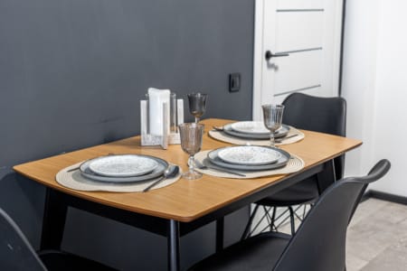 Wooden dining table with plates and glasses in the apartment in the Semytsvit complex