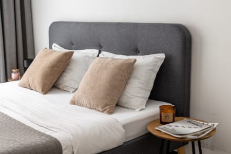 Double bed with a grey headboard and decorative cushions, apartment in the Semytsvit complex
