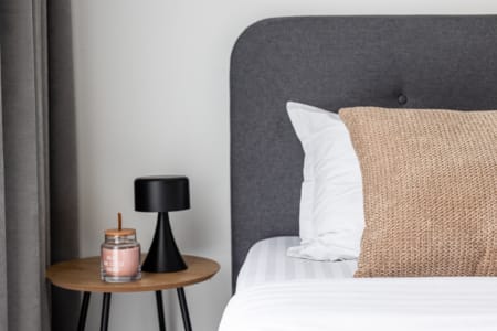 Bedside table with a lamp and a candle in the sleeping area, apartment in the Semytsvit complex