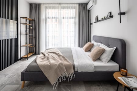 Double bed with a grey headboard and a shelving unit by the window, modern apartment in the Semytsvit complex