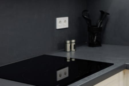 Płyta indukcyjna i ciemny fartuch w kuchni apartamentu przy ul. Doroszenki