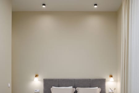 Sypialnia z wysokim sufitem i podwójnym łóżkiem w nowoczesnym apartamencie przy ul. Doroszenki