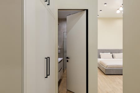Szafa i widok na sypialnię przez drzwi, nowoczesny apartament przy ul. Doroszenki