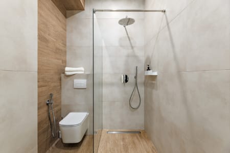 Prysznic bez brodzika ze szklaną ścianką i podwieszana toaleta w apartamencie przy ul. Doroszenki