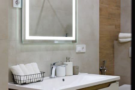 Umywalka z szafką i podświetlanym lustrem w apartamencie przy ul. Doroszenki
