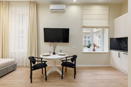 Strefa jadalna z okrągłym stołem, sofa i kuchnia w apartamencie przy ul. Doroszenki