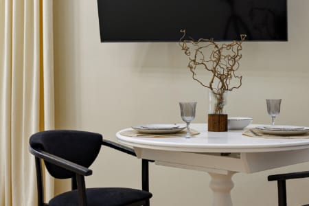Okrągły stół jadalny pod telewizorem w nowoczesnym apartamencie przy ul. Doroszenki