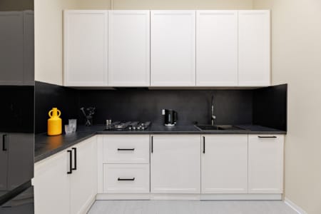 Kitchen with white cabinets and a black worktop in the apartment on Doroshenka Street in Lviv
