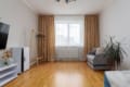 Spacious living room with a window, sofa and clothes rack in the apartment on Pluhova Street