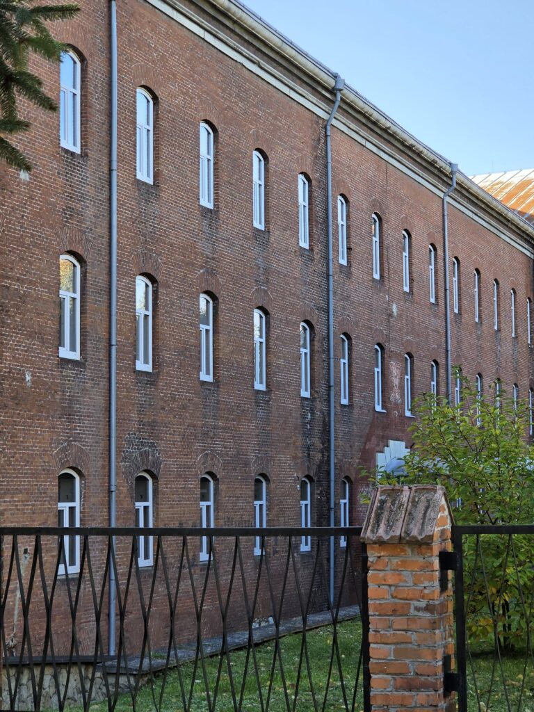 Фасад корпусу казарм Цитаделі | Leo Apartment Довгий триповерховий фасад корпусу казарм Львівської цитаделі з нетинькованої червоної цегли